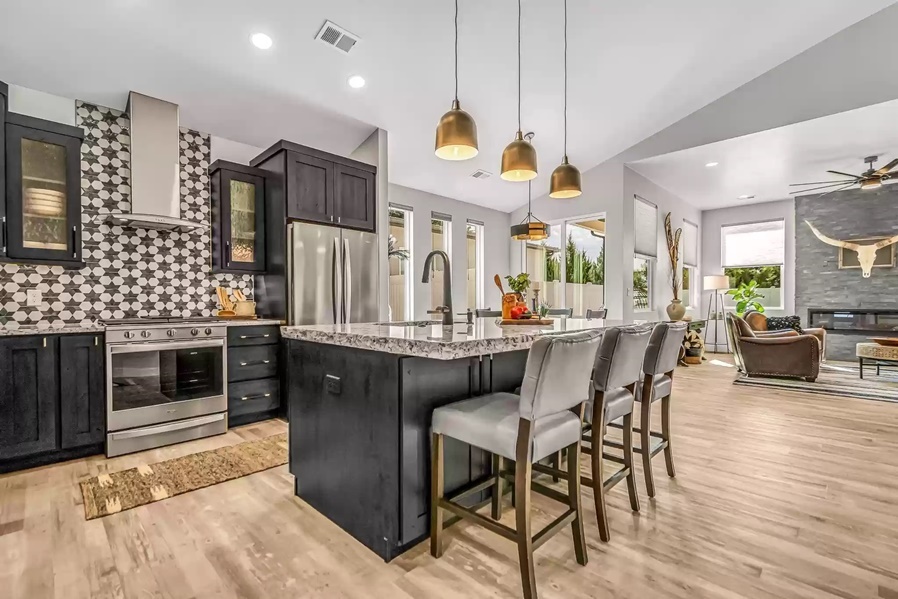 Dark cabinet kitchen with geometric mosaic backsplash and brass pendants